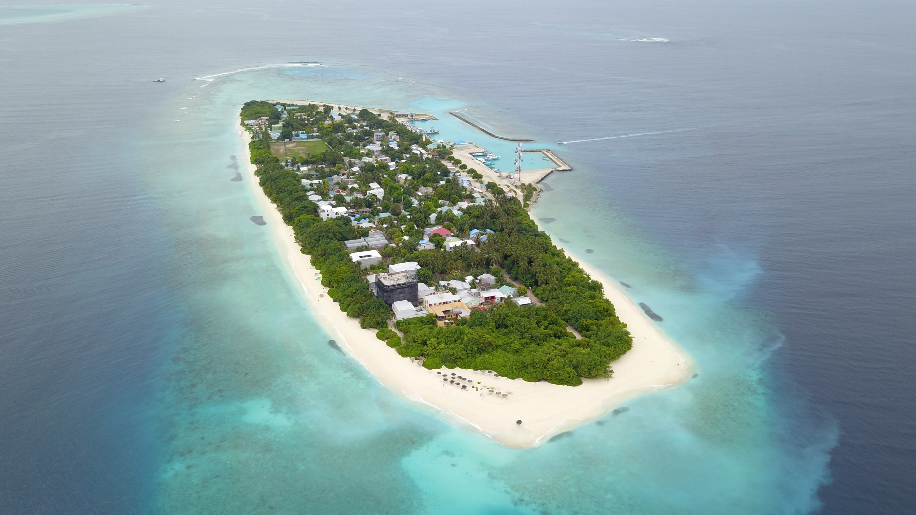 Aerial view of the entire island of Ukulhas end to end, showing the village, harbour, beach and surrounding reef