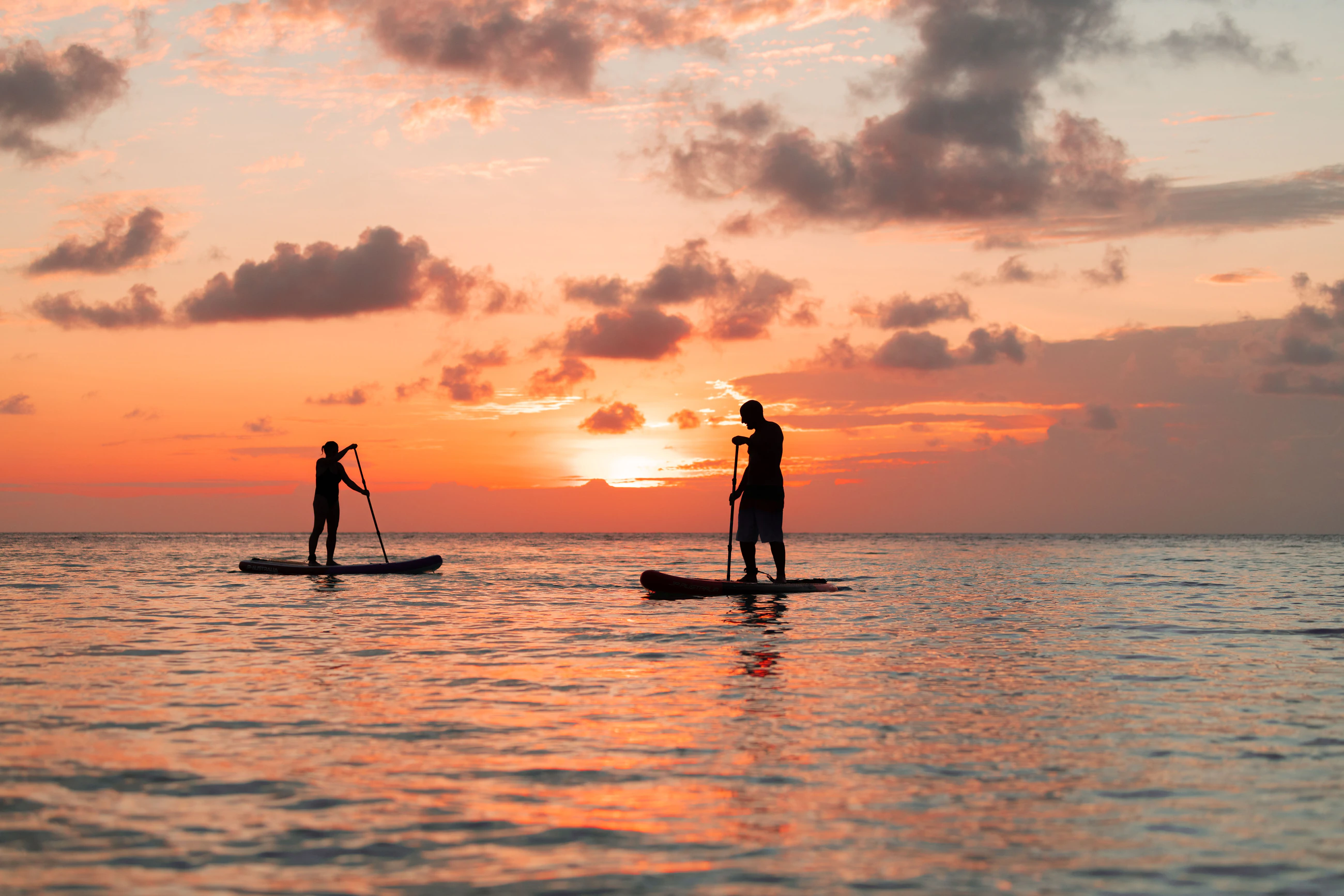 Two paddleboarders on calm water off Ukulhas at sunset