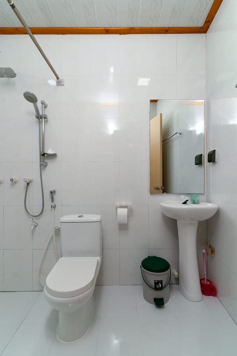 Pedestal sink in the white-tiled bathroom at Maafolhey Han'dhaan.