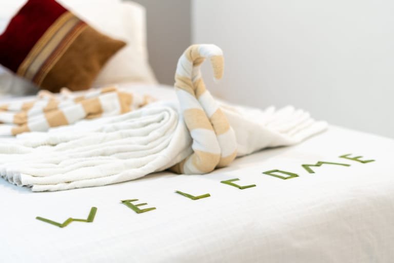 Towels folded into a swan shape on a bed at Maafolhey Han'dhaan.