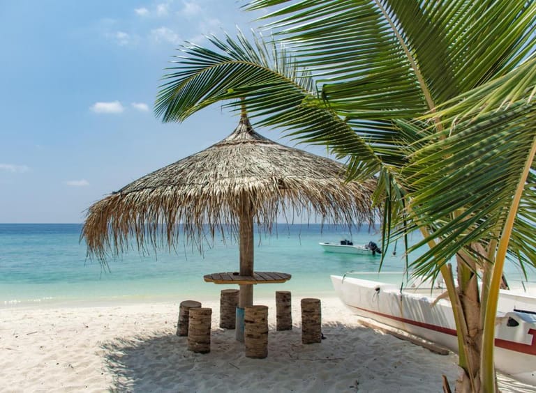 Ukulhas main beach: white sand, clear turquoise water, shaded seating